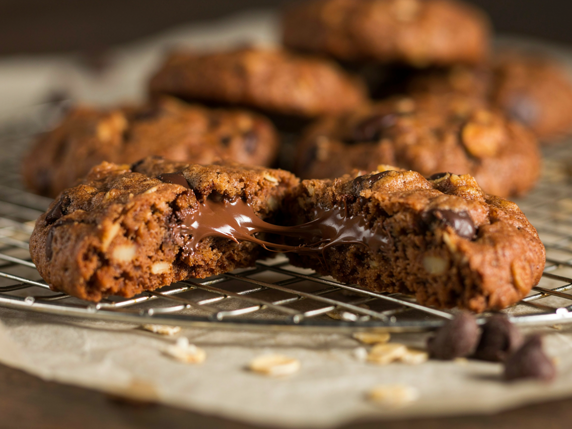 A chocolate chip oatmeal cookie broken in half showing a soft chewy center