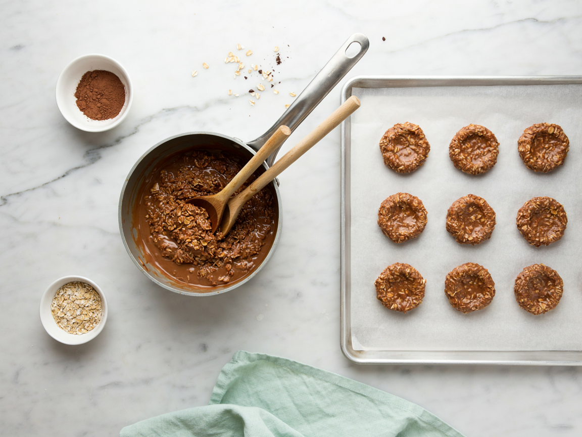 Saucepan of chocolate oat mixture beside freshly scooped no bake cookies