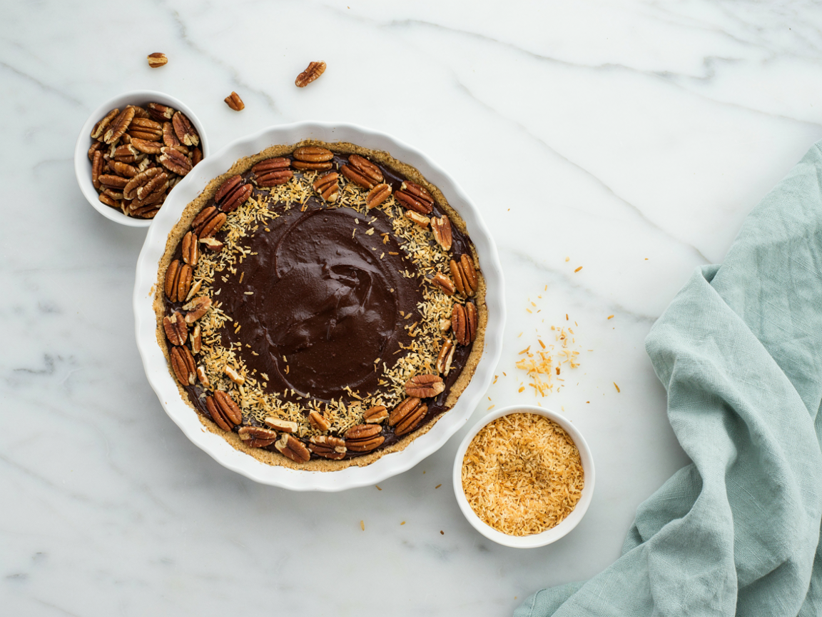 Whole no bake German chocolate pie topped with pecan halves and toasted coconut